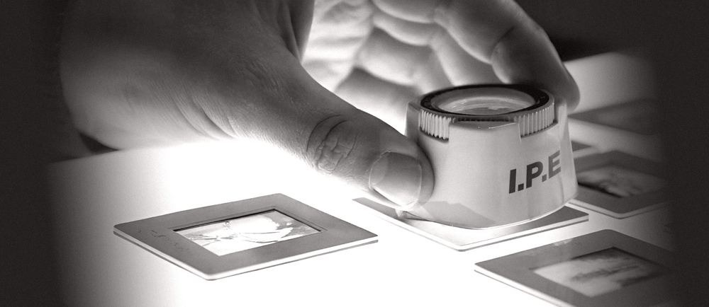 Main tenant un compte-fils marqué I.P.E au-dessus de diapositives sur table lumineuse
